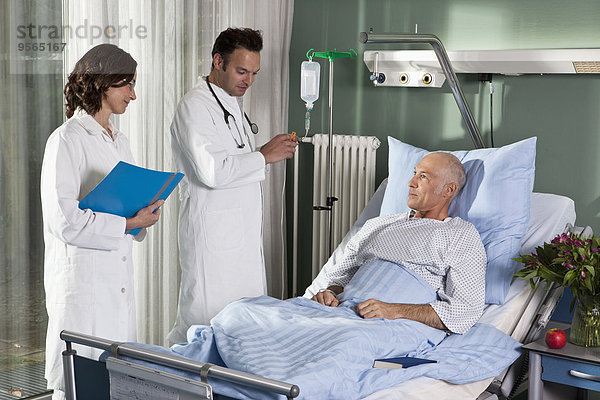 Zwei Ärzte mit einem männlichen Patienten auf einer Krankenstation