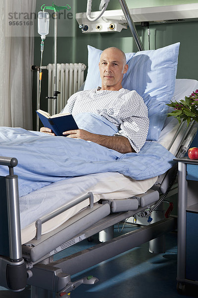 Porträt eines Mannes mit einem Buch im Krankenhausbett