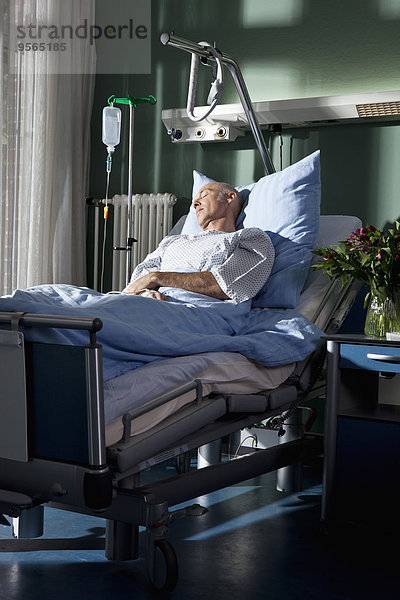 Ein Mann  der in einem Krankenhausbett schläft.