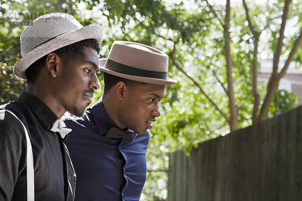 Zwei junge schwarze Männer mit Fliege und Hut  die weggucken.