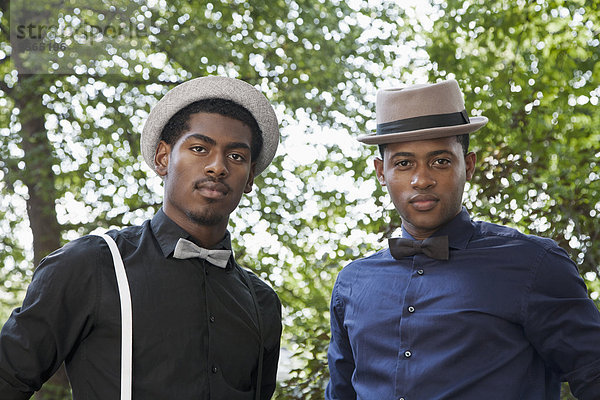 Zwei hübsche junge schwarze Männer mit Fliege und Hut.