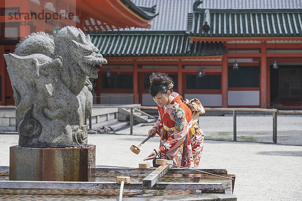 Mittlere erwachsene Frau beim Händewaschen gegen den Tempel