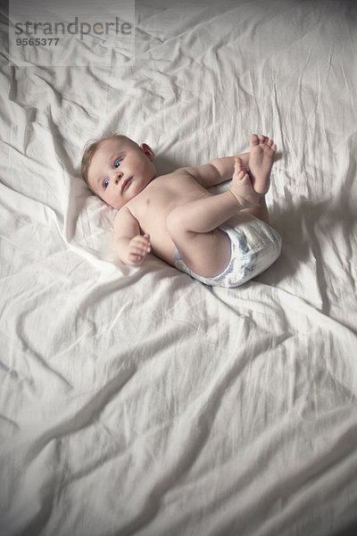 Baby in Windel auf dem Rücken liegend mit erhobenen Beinen