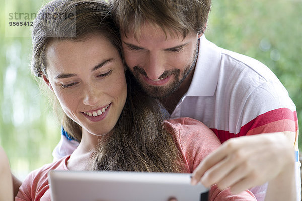 Junges Paar mit digitalem Tablett zusammen im Freien