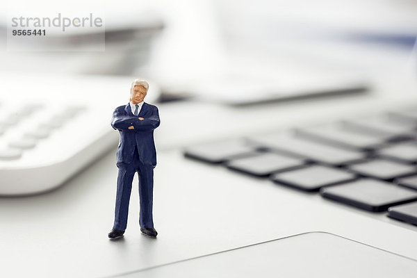 Geschäftsmann-Figur stehend auf Laptop-Tastatur