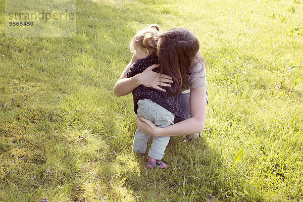 Mutter umarmt das Mädchen im Freien