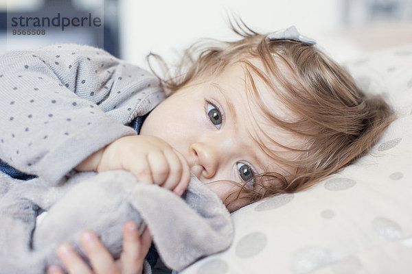 Kleines Mädchen liegend  Daumen lutschend  Portrait