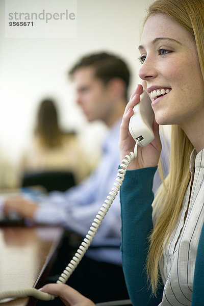 Frau mit Festnetztelefon im Büro