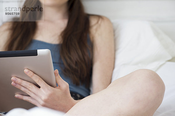 Frau mit digitalem Tablett im Bett