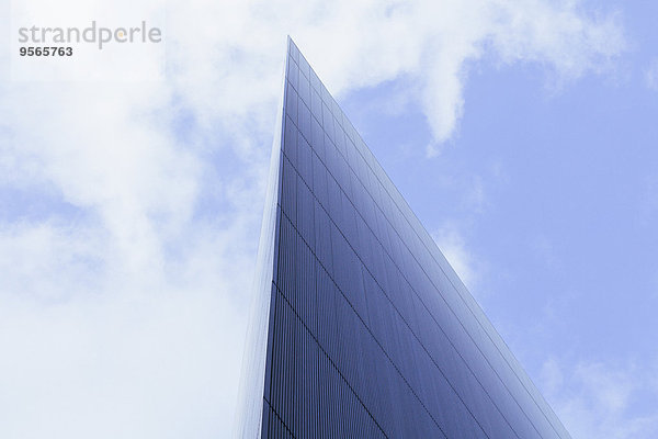 Flachwinkelansicht eines modernen Glasgebäudes gegen bewölkten Himmel