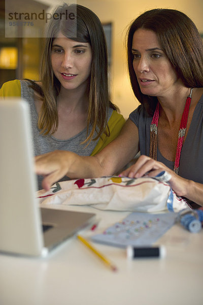 Mutter und Tochter lernen gemeinsam Stickerei  indem sie sich Online-Videos anschauen.
