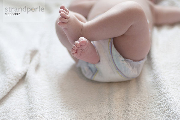 Baby in Windel auf dem Rücken liegend mit hochgezogenen Beinen  abgeschnitten