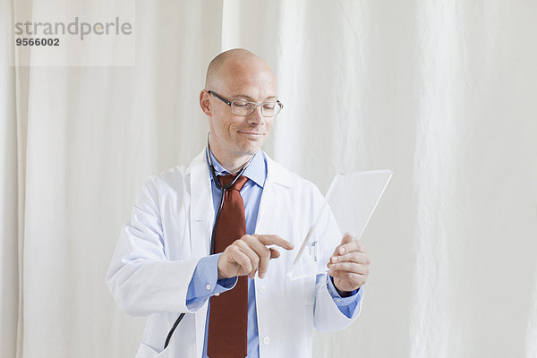 Männlicher Arzt berührt futuristisches digitales Tablett in der Klinik