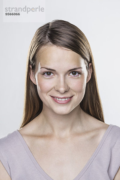 Nahaufnahme Porträt einer lächelnden jungen Frau vor weißem Hintergrund