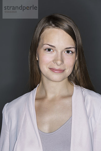 Porträt einer lächelnden jungen Frau vor schwarzem Hintergrund