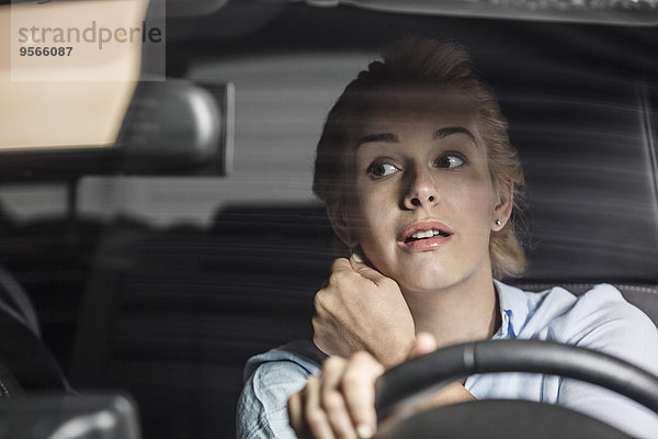 Mittlere erwachsene Frau im Rückspiegel beim Autofahren