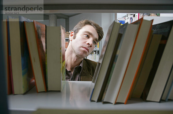 Ein Mann bewertet Bücher im Bücherregal.