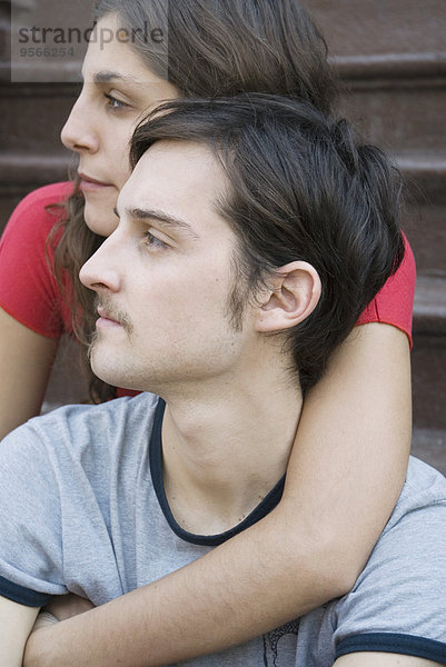 Junge Frau sitzt hinter jungem Mann