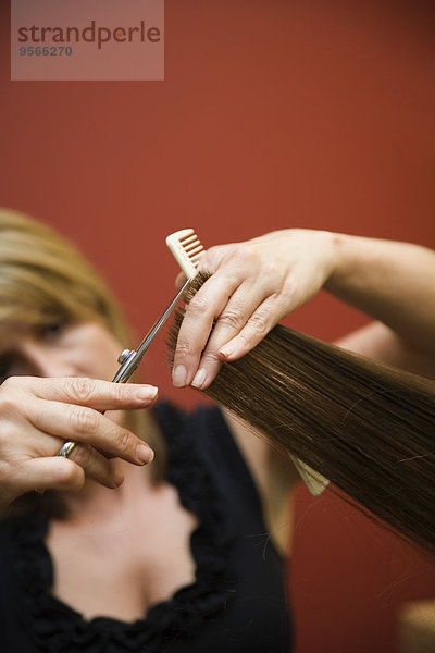 Ein Friseur  der einer Frau die Haare schneidet.