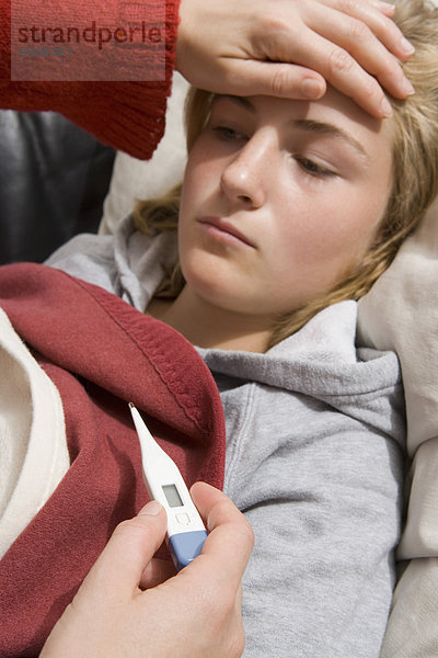 Teenager Mädchen liegend mit Fieber  digitales Thermometer