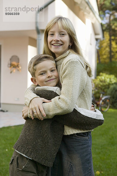 Bruder und Schwester umarmen sich im Garten