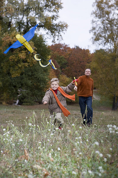 Vater und Sohn beim Drachenfliegen im Herbst