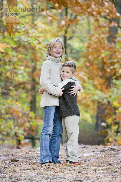 Bruder und Schwester umarmen sich im Wald