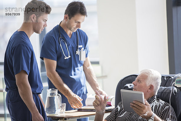 Patient mit Tablet-PC und Gespräch mit Ärzten im Krankenhaus