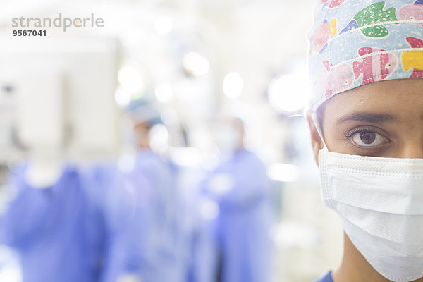 Portrait des maskierten Chirurgen mit unscharfer Krankenhauseinstellung im Hintergrund