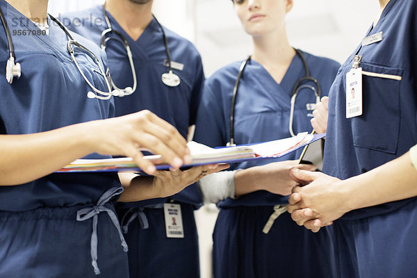 Ärzteteam mit Stethoskopen beim Betrachten von Dokumenten im Krankenhaus