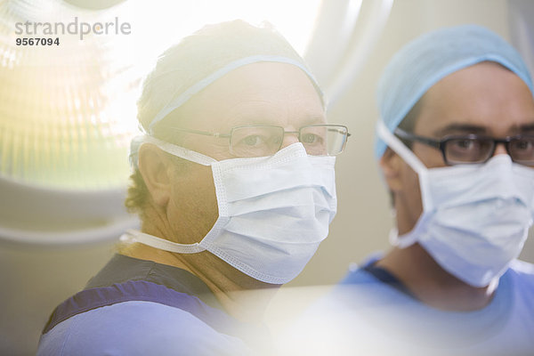 Portrait von zwei Ärzten mit OP-Kappen  Masken und Brillen im Operationssaal