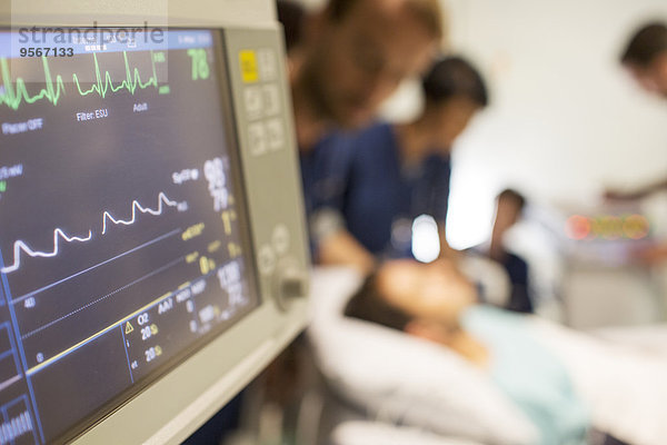 Herzfrequenzmonitor  Patient und Ärzte im Hintergrund auf der Intensivstation