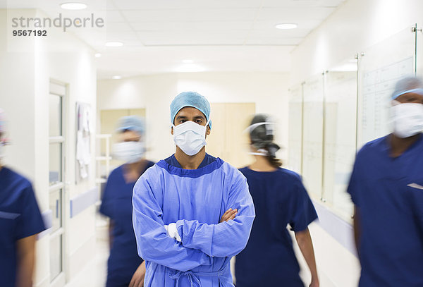 Chirurg mit gekreuzten Armen  mit Peelings im Krankenhausflur stehend