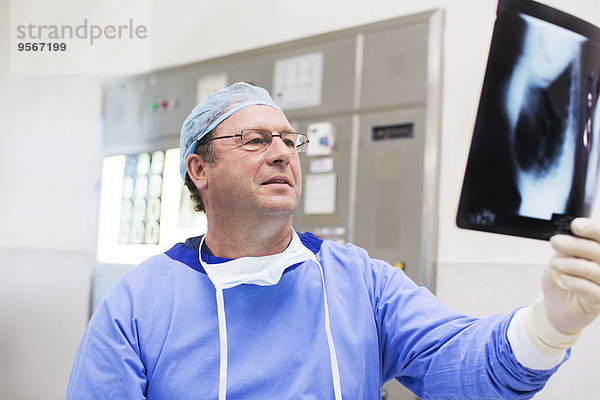 Arzt mit OP-Kappe und OP-Kittel beim Röntgen im Operationssaal