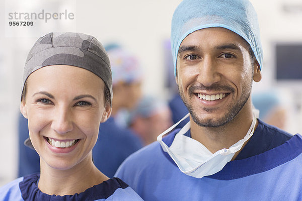 Porträt von lächelnden Ärzten mit OP-Hauben im Operationssaal