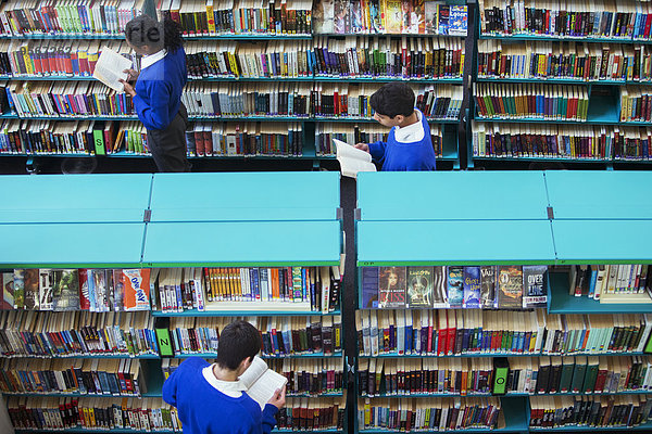 Erhöhte Ansicht von Gymnasiasten beim Durchstöbern von Büchern in der Bibliothek