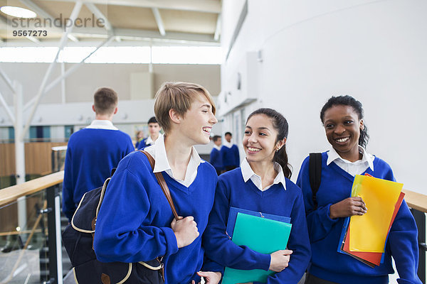 Lächelnde Schülerinnen in Schuluniformen gehen durch den Schulflur