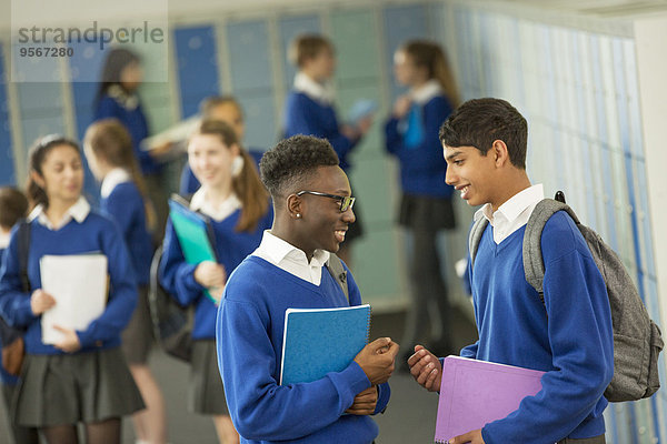 Zwei männliche Schüler in Schuluniformen sprechen in der Umkleide.