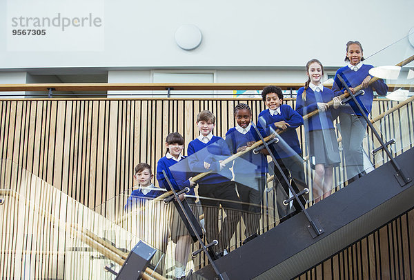 Porträt von Grundschulkindern in blauen Schuluniformen  die auf Stufen in der Schule stehen.