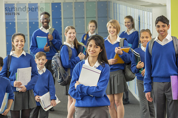 Gruppenporträt von Schülern in Schuluniform im Flur stehend und lächelnd