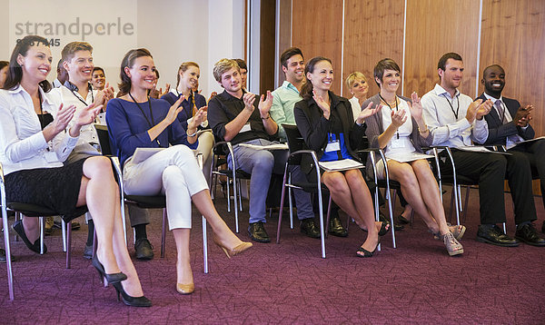 Geschäftsleute bei der Präsentation im Konferenzraum  beim Händeklatschen und Lächeln