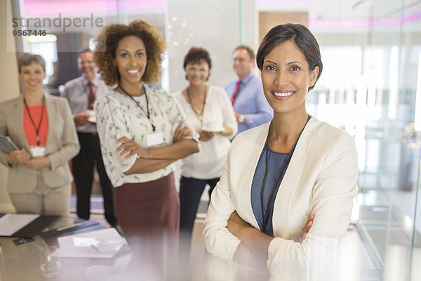 Porträt einer selbstbewussten Geschäftsfrau  mit Kollegen im Hintergrund im Konferenzraum