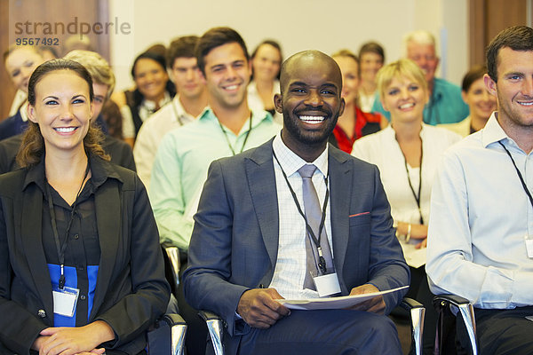 Lächelnder Geschäftsmann sitzt im Konferenzraum und schaut in die Kamera.