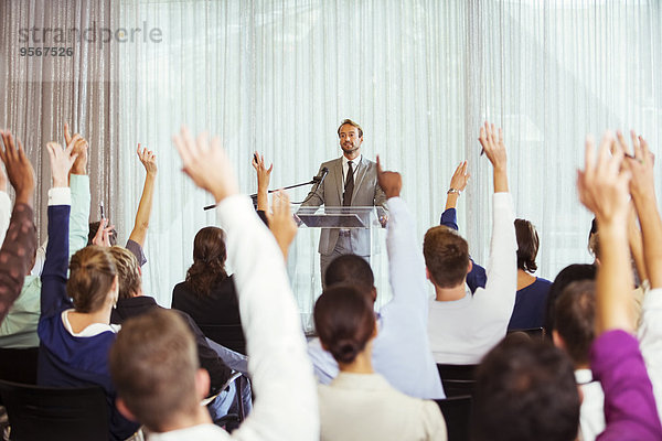 Geschäftsmann bei der Präsentation im Konferenzraum  Menschen heben die Hand