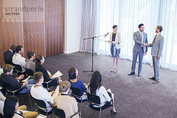 Öffentliche Redner schütteln während der Konferenz die Hände auf der Bühne