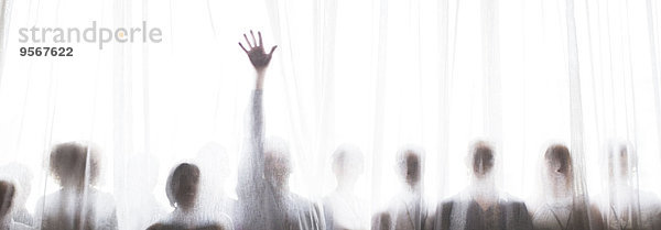 Silhouette von Menschen hinter transparentem Vorhang  eine Person hebt die Hand