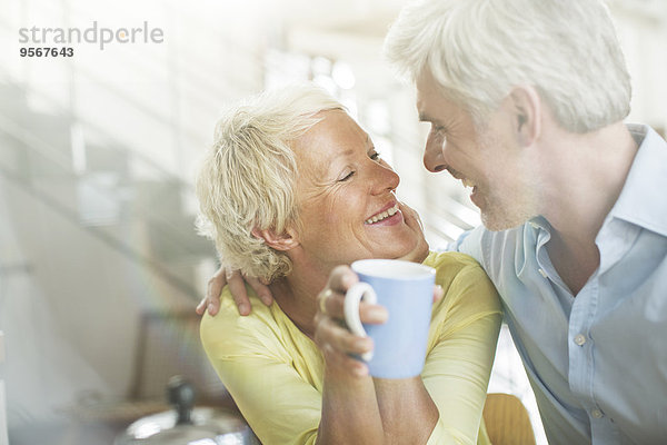 Ältere Paare umarmen sich mit Kaffeetasse