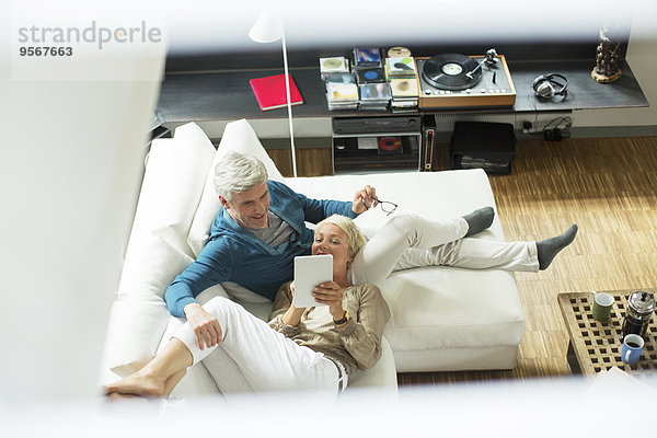 Hochwinkelansicht des älteren Paares mit digitalem Tablett auf dem Sofa