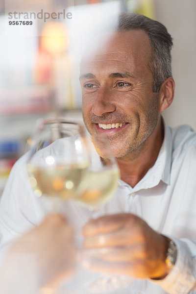 Lächelnder älterer Mann beim Toasten mit Weißwein