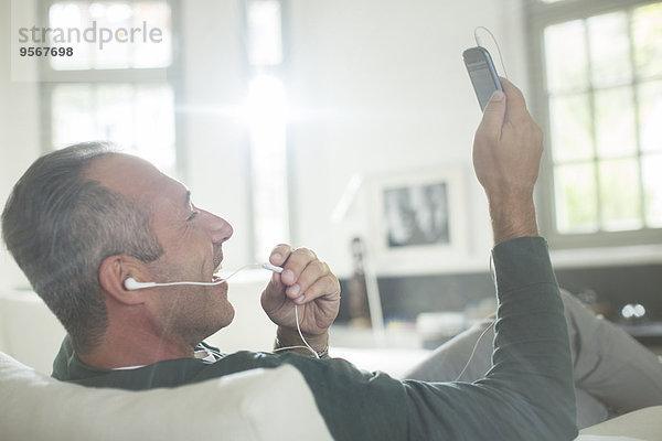 Nahaufnahme eines älteren Mannes mit Ohrhörern am Handy